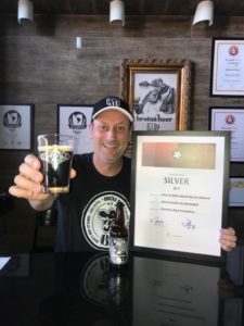 homem segurando o premio e um copo de cerveja schwarzbier